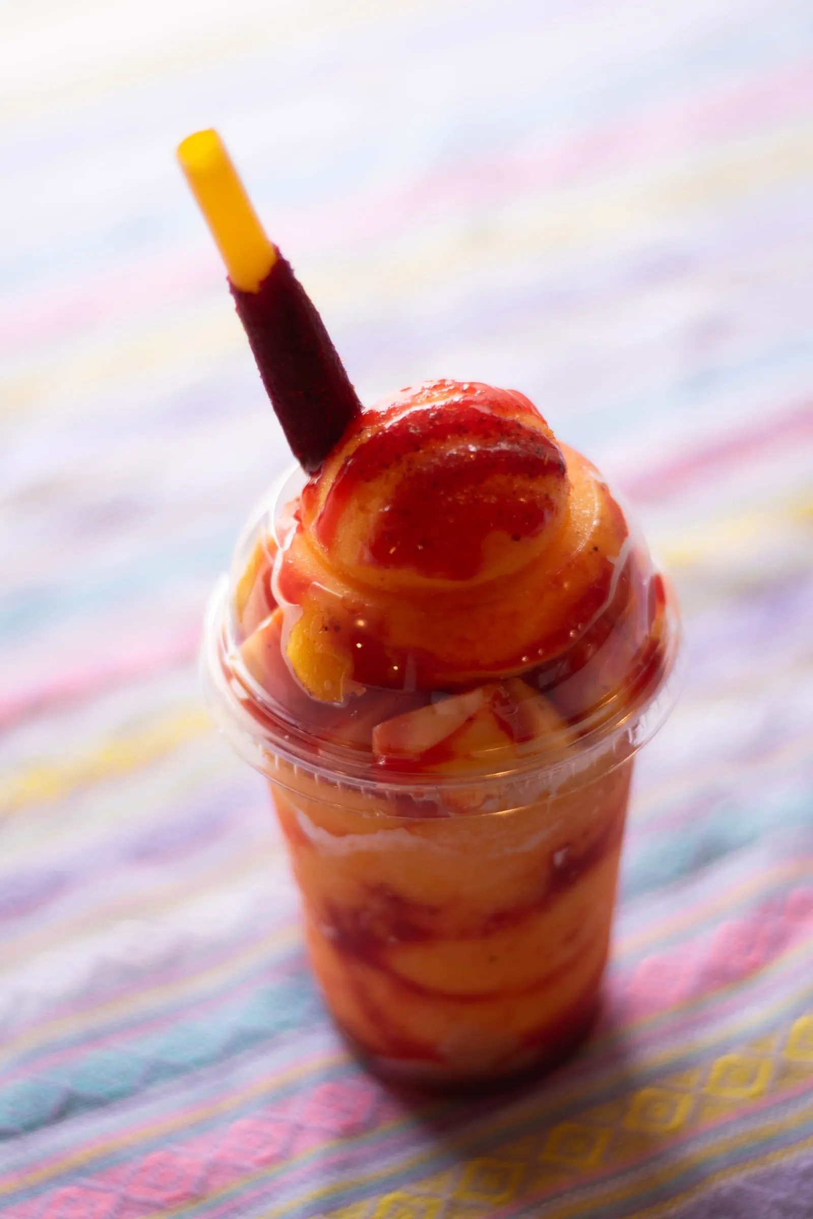 A mangonada in a cup with chamoy and a tamarind straw