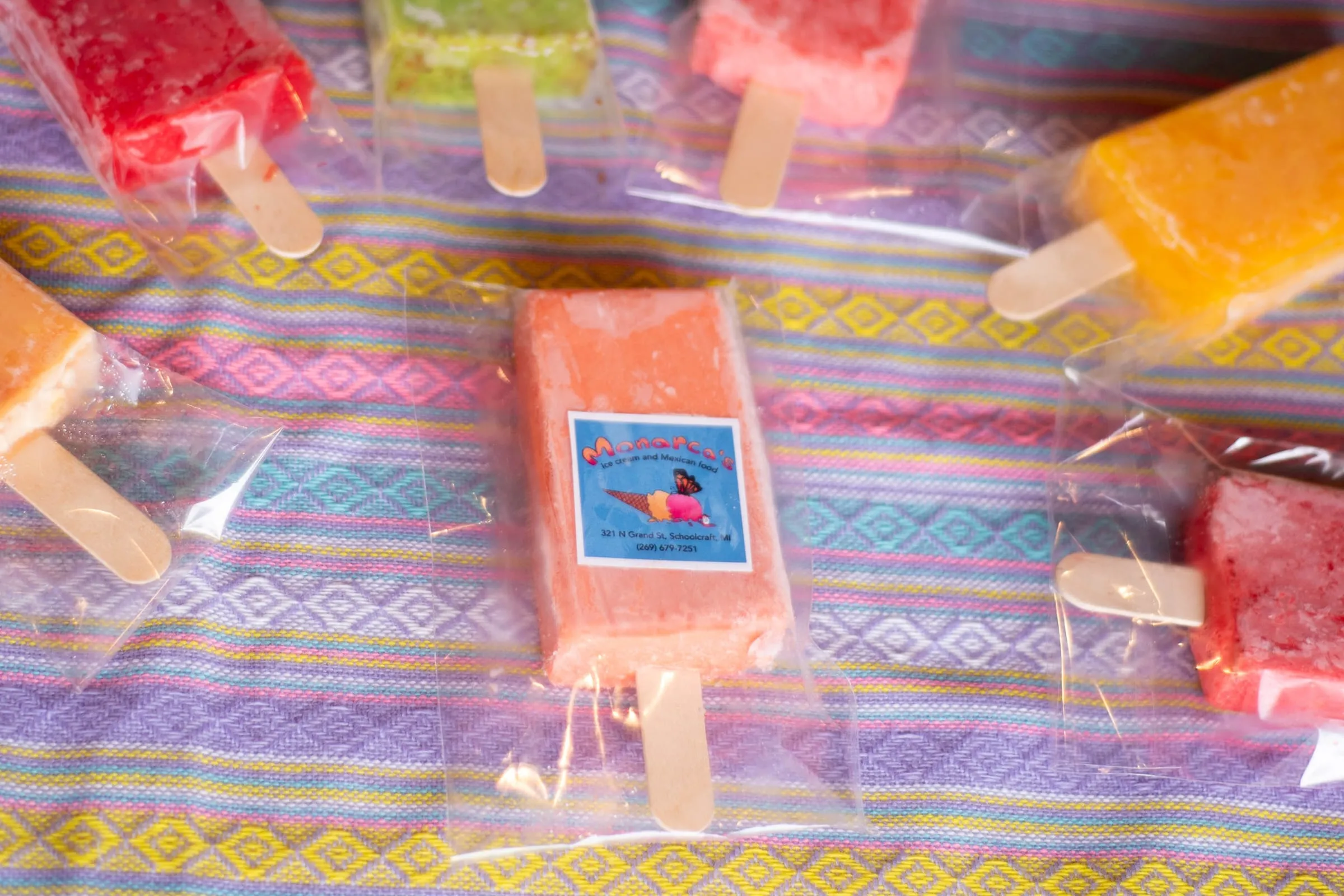Paletas in several colors laid out on a striped cloth