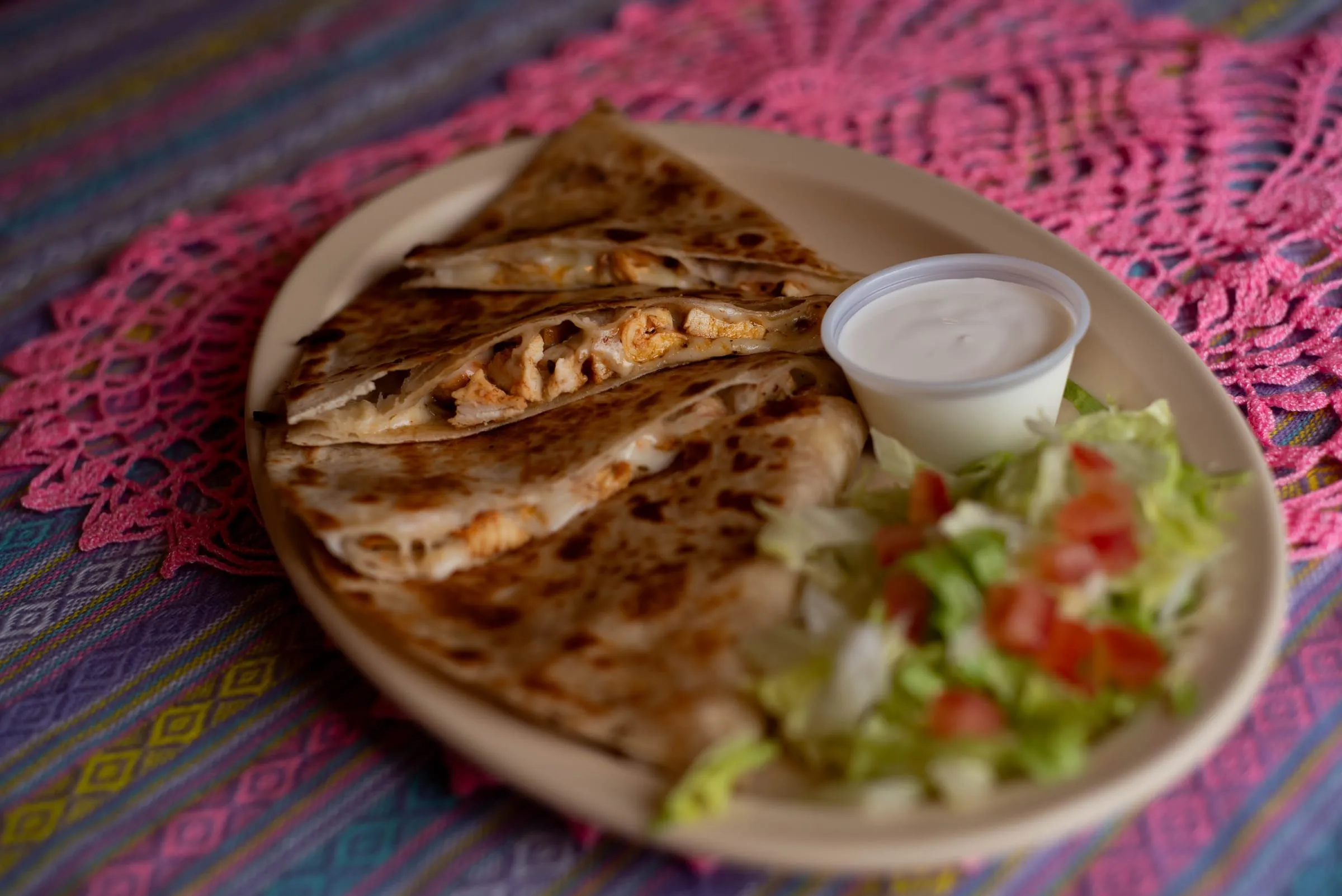 A grilled quesadilla cut into wedges with lettuce and tomato
