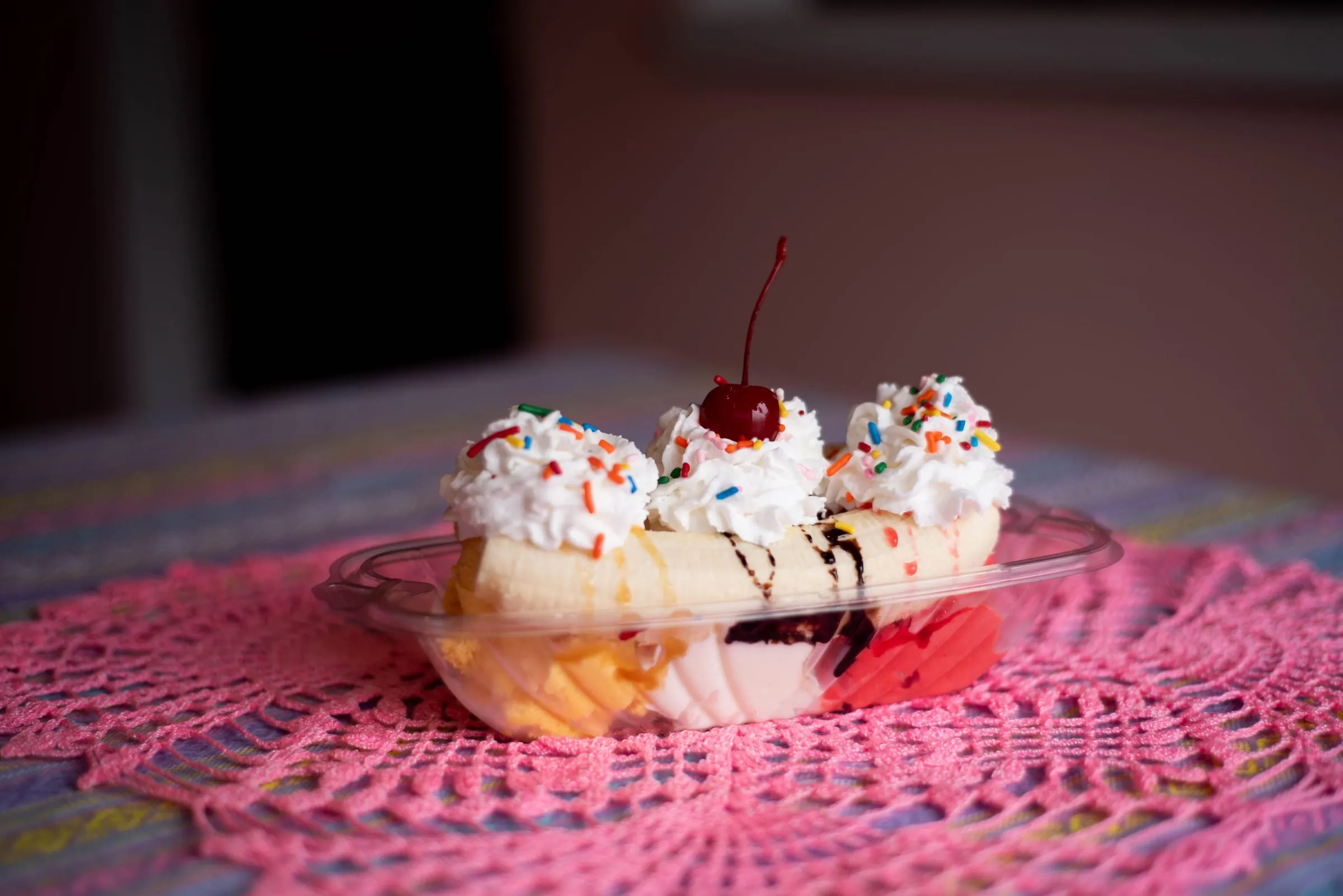 A banana split with whipped cream, sprinkles and a cherry